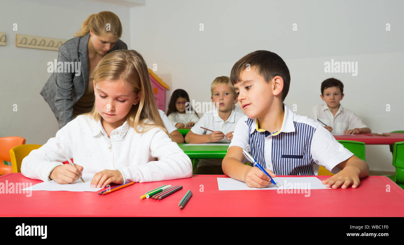 Felice di chattering alunni seduti a lezione a scuola elementare Foto Stock