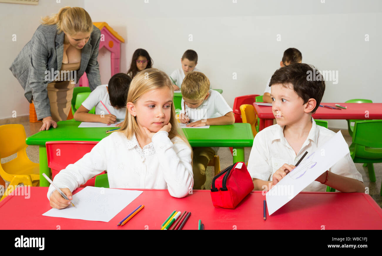 Felice di chattering alunni seduti a lezione a scuola elementare Foto Stock