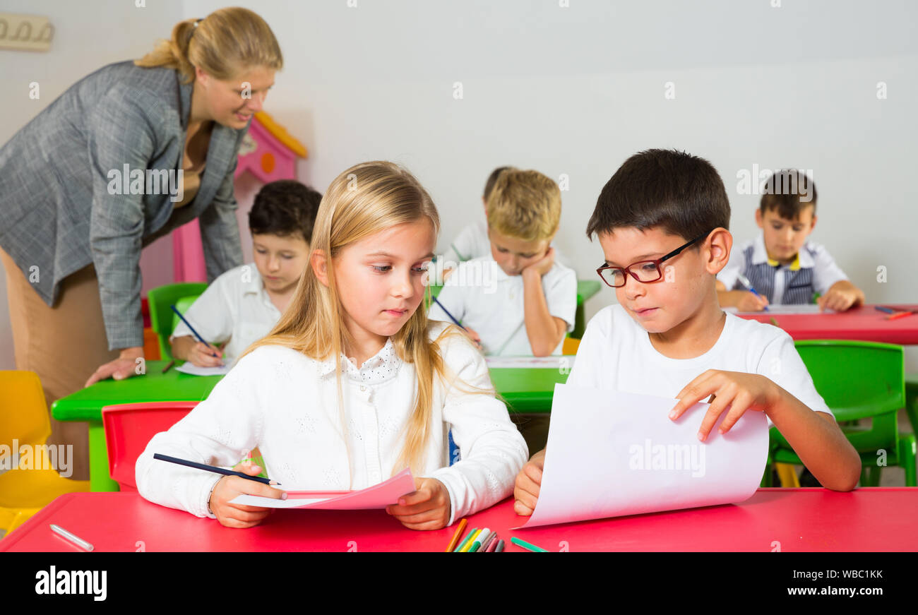 Felice di chattering alunni seduti a lezione a scuola elementare Foto Stock