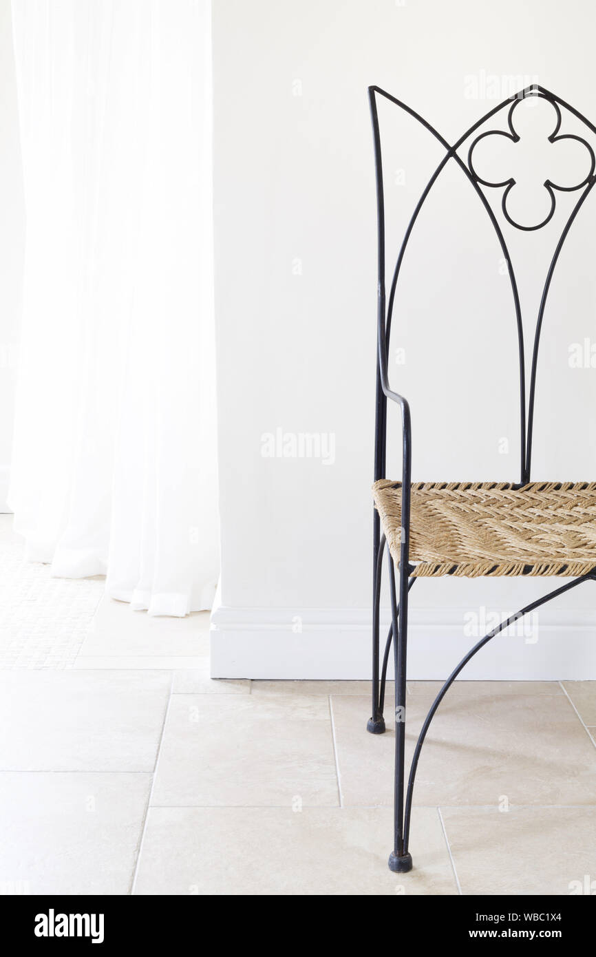 Ferro battuto sedia moderna contro una parete in una casa interno Foto Stock