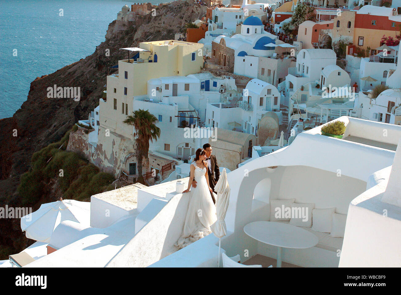 Oia - Santorini, Grecia - 7-07-2016: la sposa e lo sposo che pongono tra Santorini case bianche e blu con vista sul mare. Nozze il concetto di turismo Foto Stock