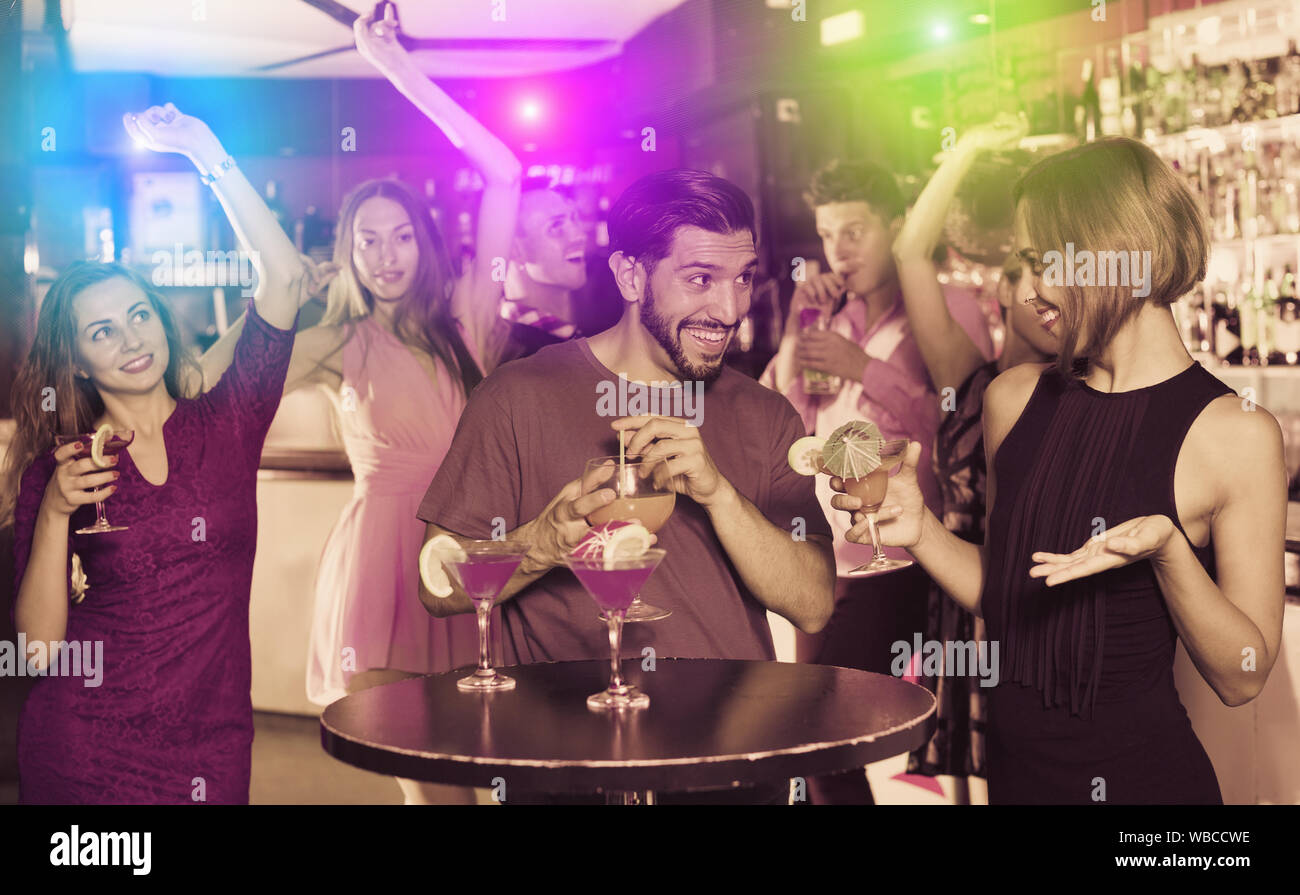 Adulto felice maschio con due femmine sono a parlare e a bere un cocktail sulla parte. Foto Stock