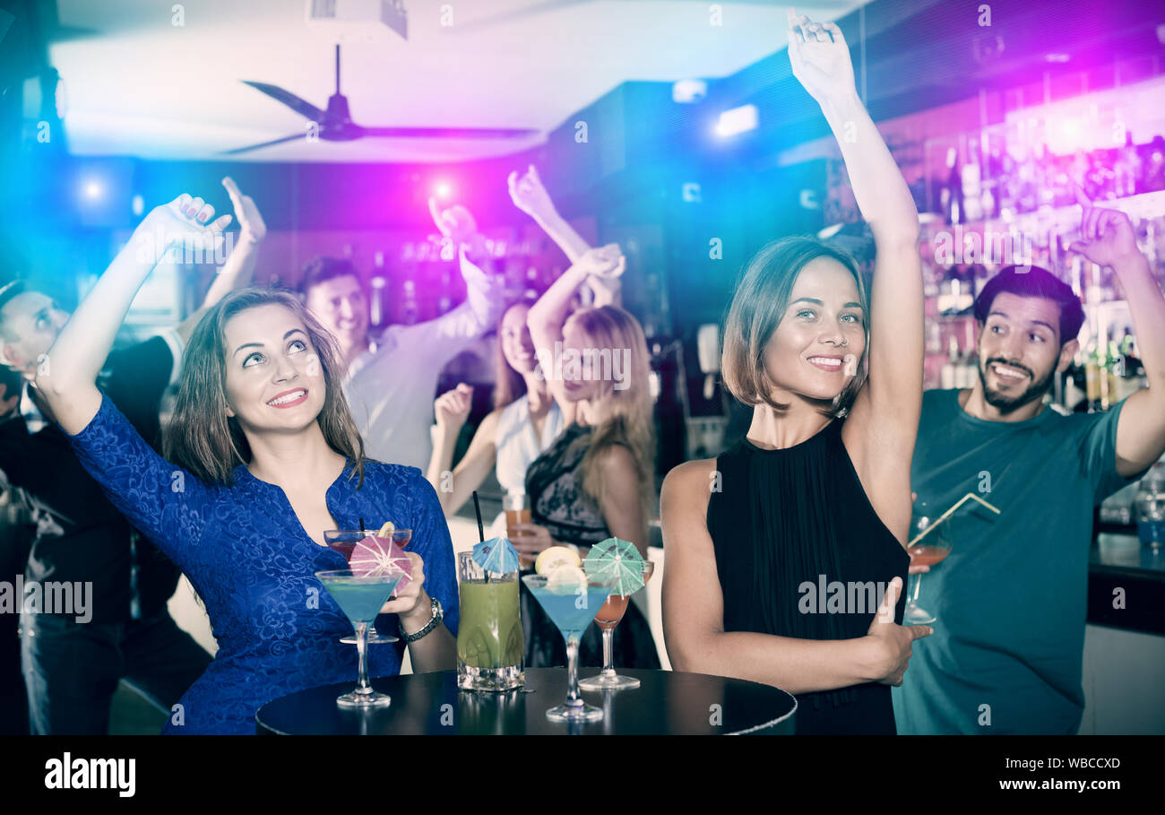 Felice maschio con due femmine sono a parlare e a bere un cocktail sulla parte. Foto Stock