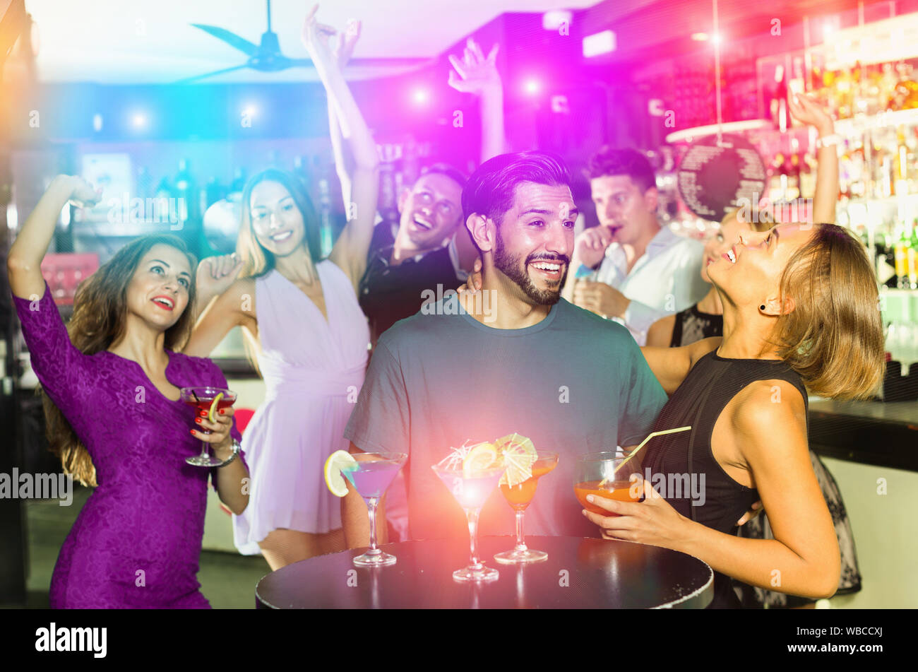 Allegro uomo sorridente con giovani donne stanno godendo il partito in bar. Foto Stock