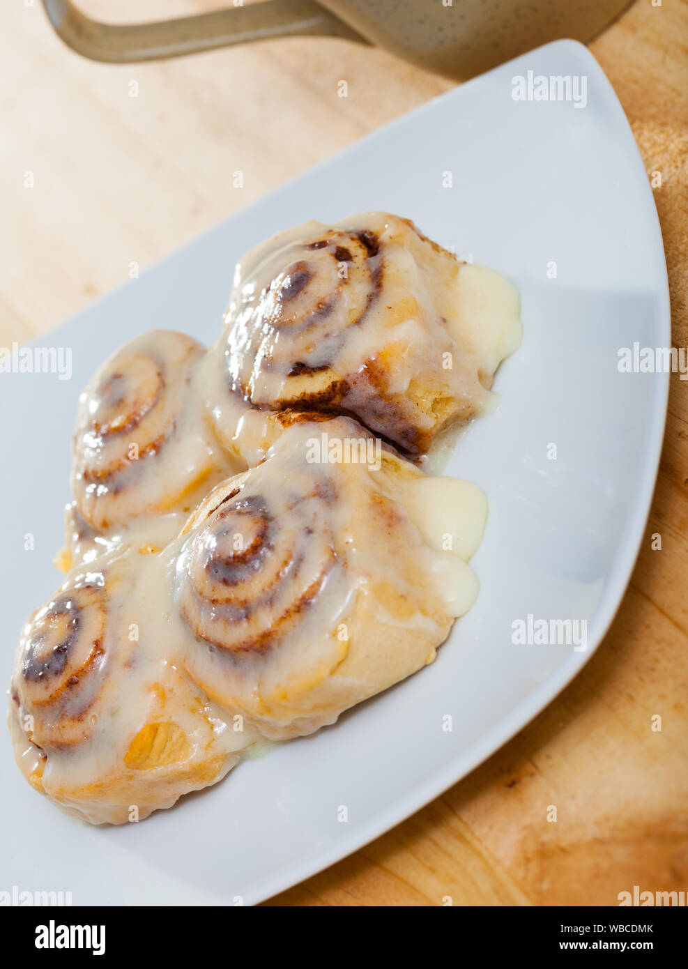 Laminati appetitosi panini alla cannella in zucchero e vaniglia ciliegina sulla piastra bianca Foto Stock