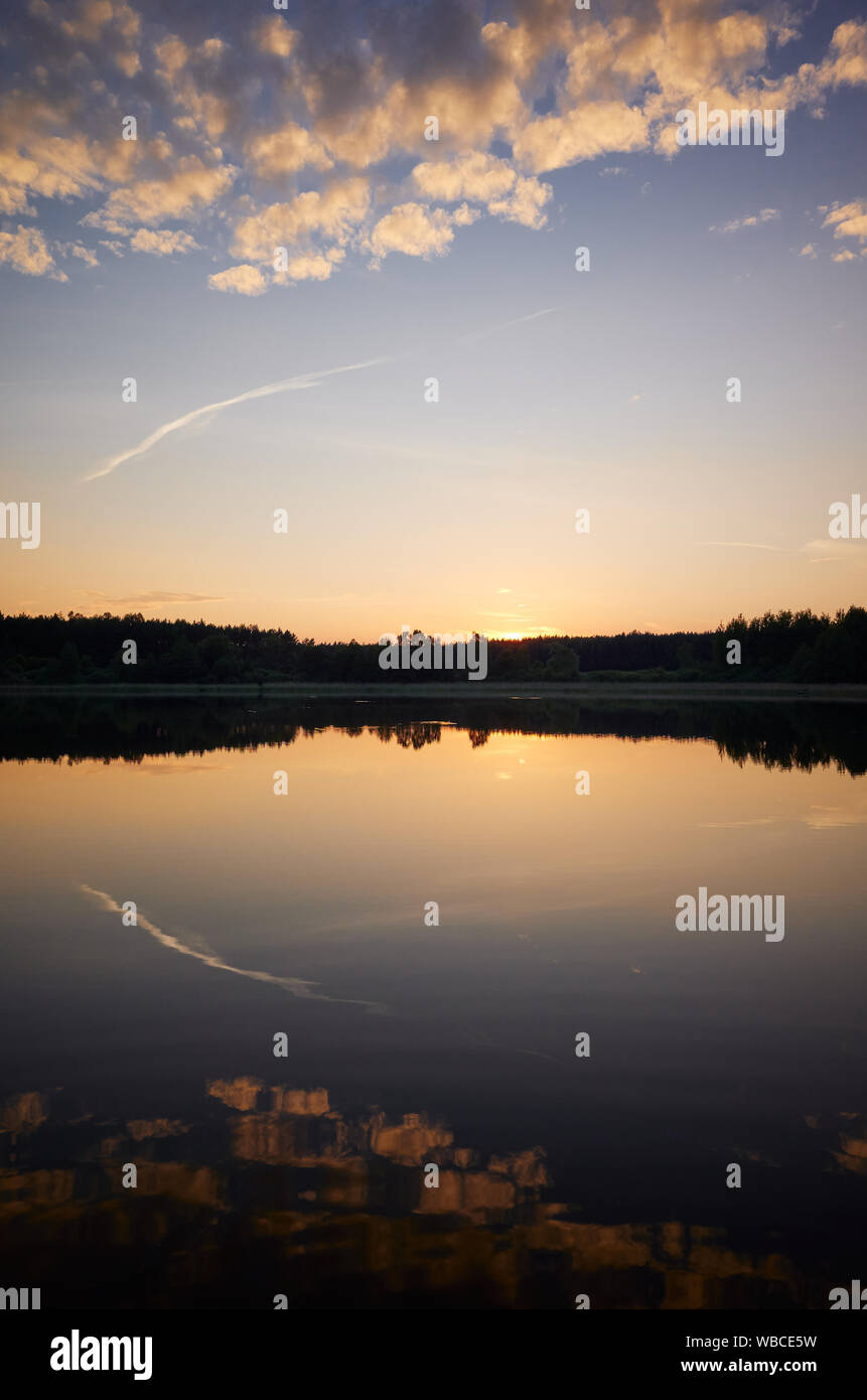 Silhouette di un lago con riflette il cielo al tramonto. Foto Stock