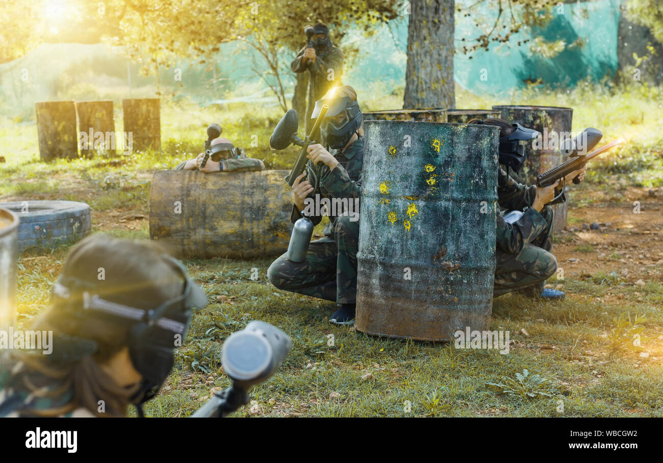 Gruppo di amici giocatori di paintball in camuffamento di suonare insieme in battaglia nella foresta all'aperto Foto Stock