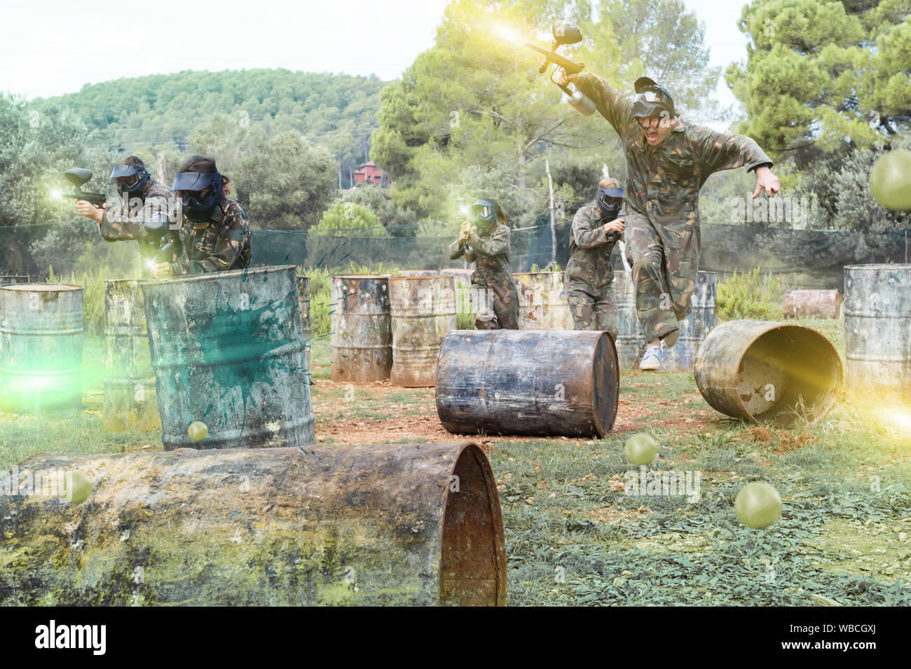 Dynamic paintball battaglia all'esterno. Gruppo di persone in camuffamento attaccando squadra opposta Foto Stock