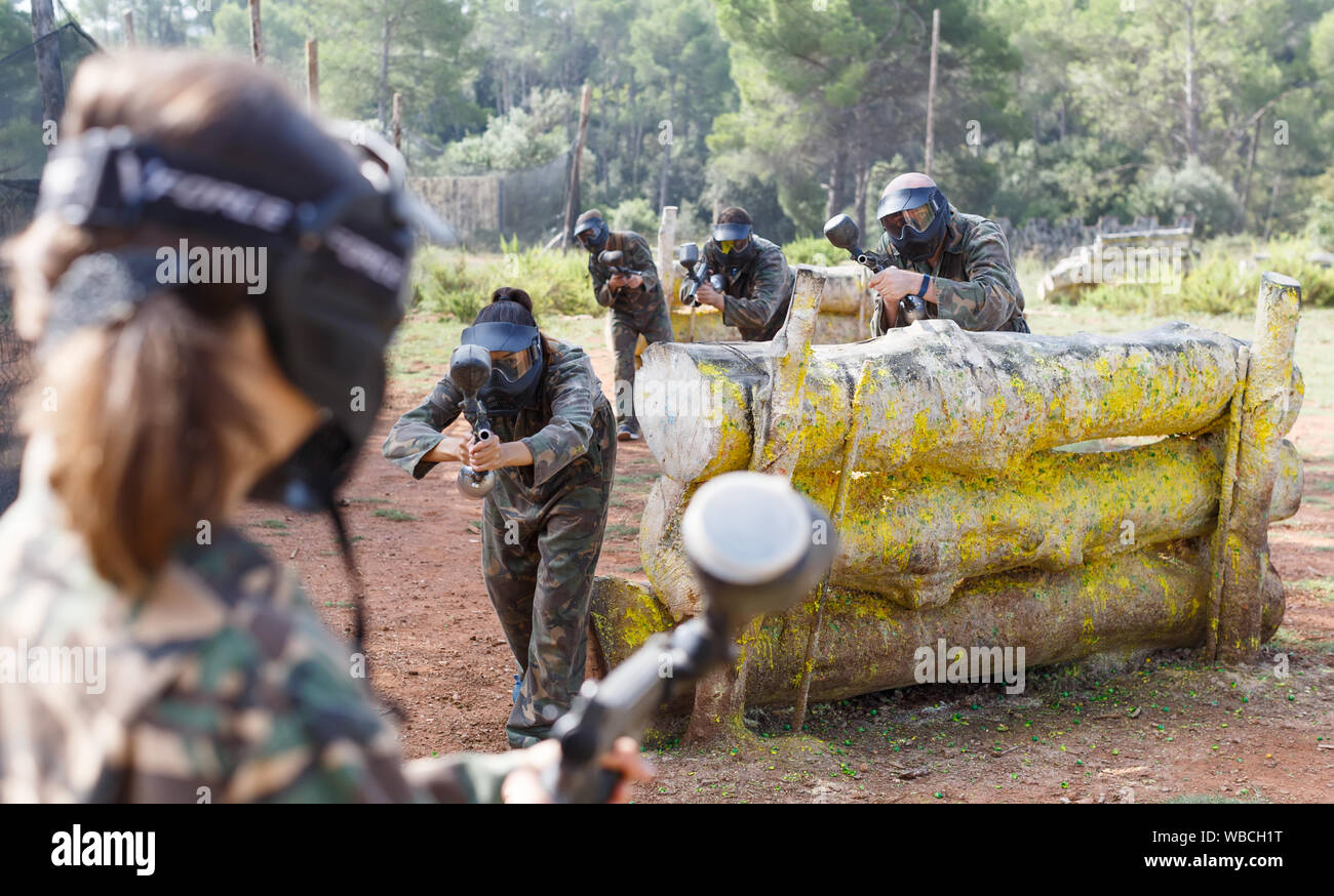Gruppo di fronte ai giocatori di paintball in camuffamento con pistole a giocare in battaglia nella foresta all'aperto Foto Stock