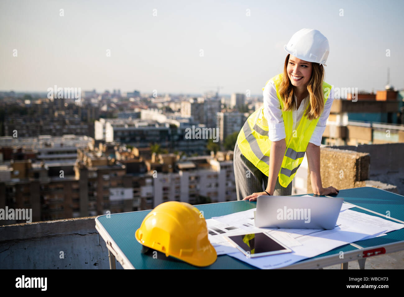 Giovani femmine costruzione ingegnere specializzato rivedendo blueprint al sito in costruzione Foto Stock