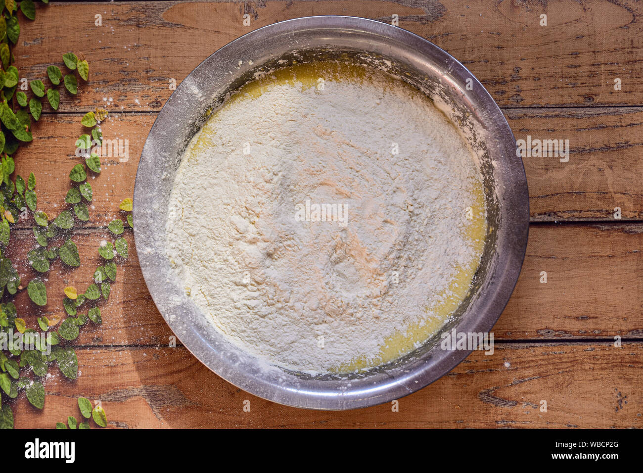 Ciotola con gli ingredienti per fare una senza glutine Banana torta su una superficie in legno con foglie di colore verde Foto Stock