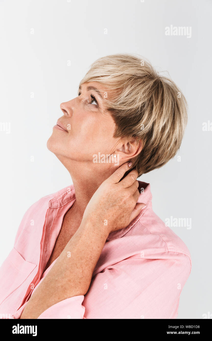 Ritratto closeup di matura donna di mezza età con corti capelli biondi guardando verso l'alto a copyspace isolato su sfondo bianco in studio Foto Stock