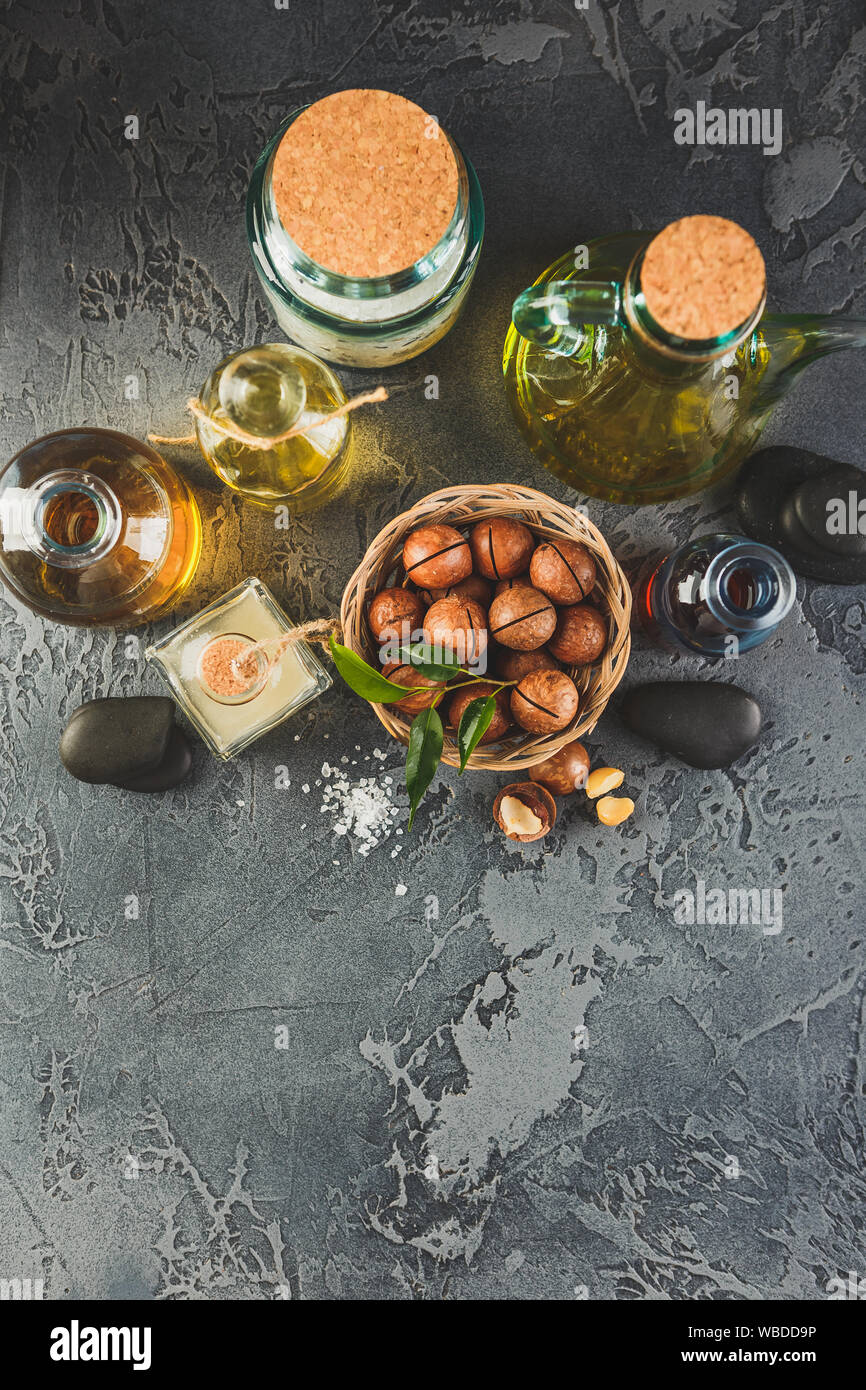 Bottiglie di vetro con naturale olio di macadamia con noci macadamia, sale marino e pietre zen. Super e cibo sano concetto Foto Stock