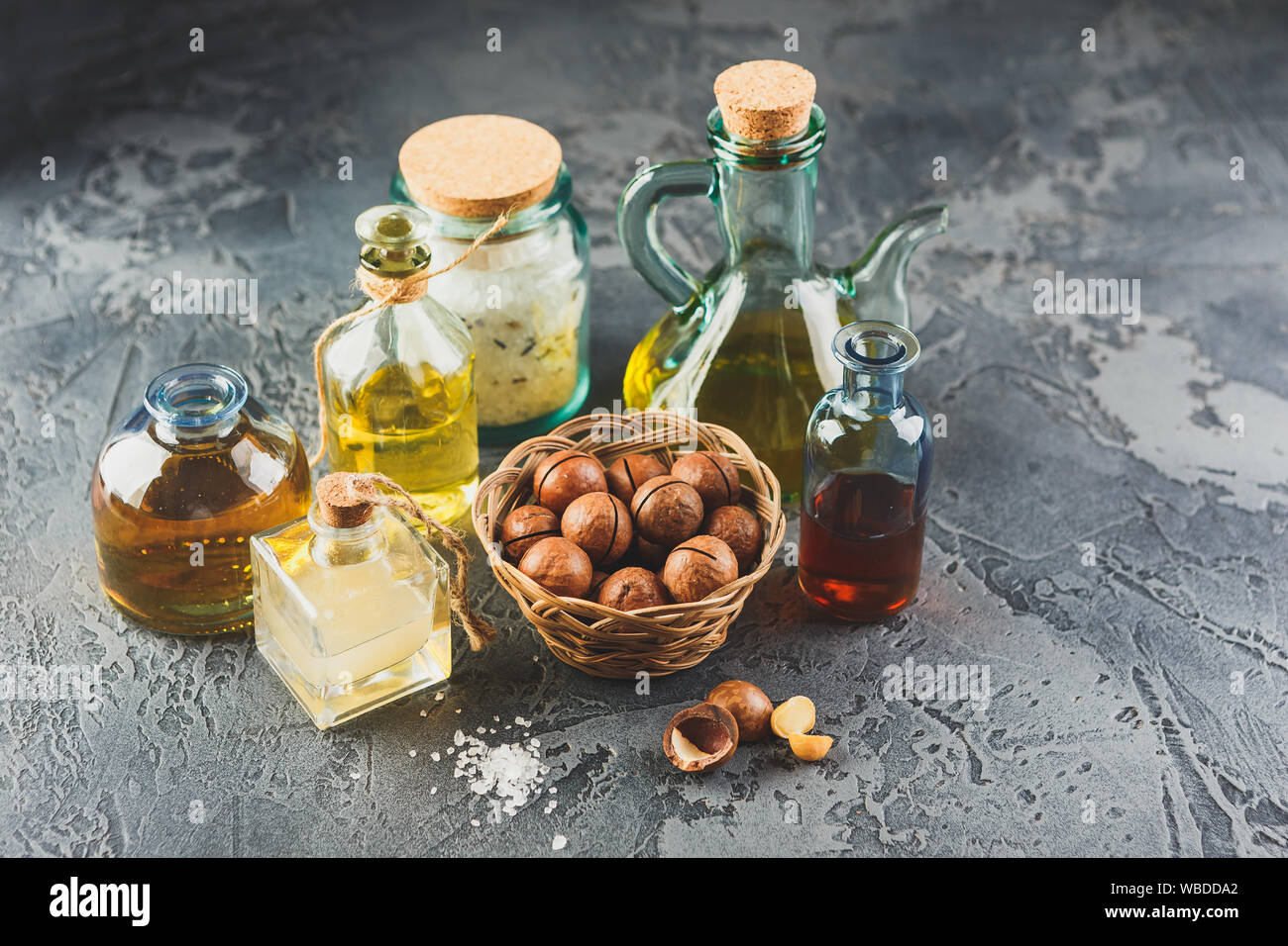 Bottiglie di vetro con naturale olio di macadamia con noci macadamia, sale marino e pietre zen. Super e cibo sano concetto Foto Stock