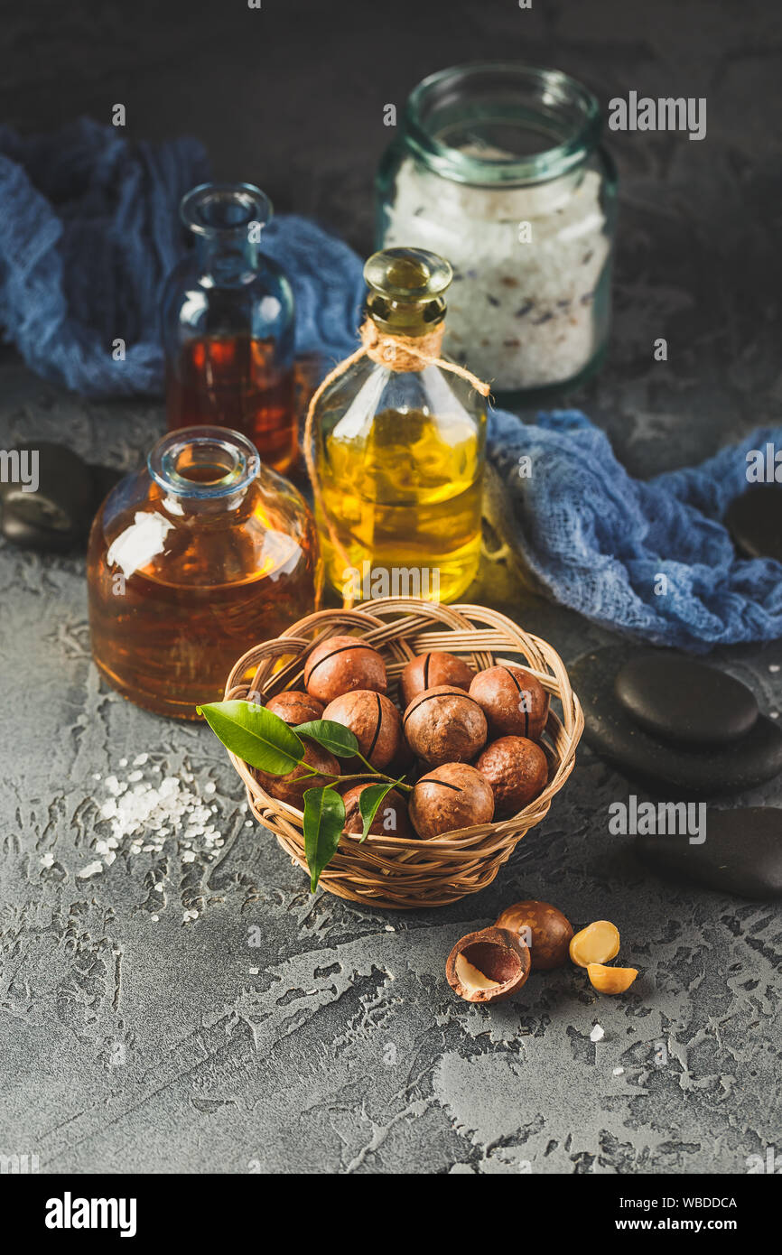 Bottiglie di vetro con naturale olio di macadamia con noci macadamia, sale marino e pietre zen. Super e cibo sano concetto Foto Stock