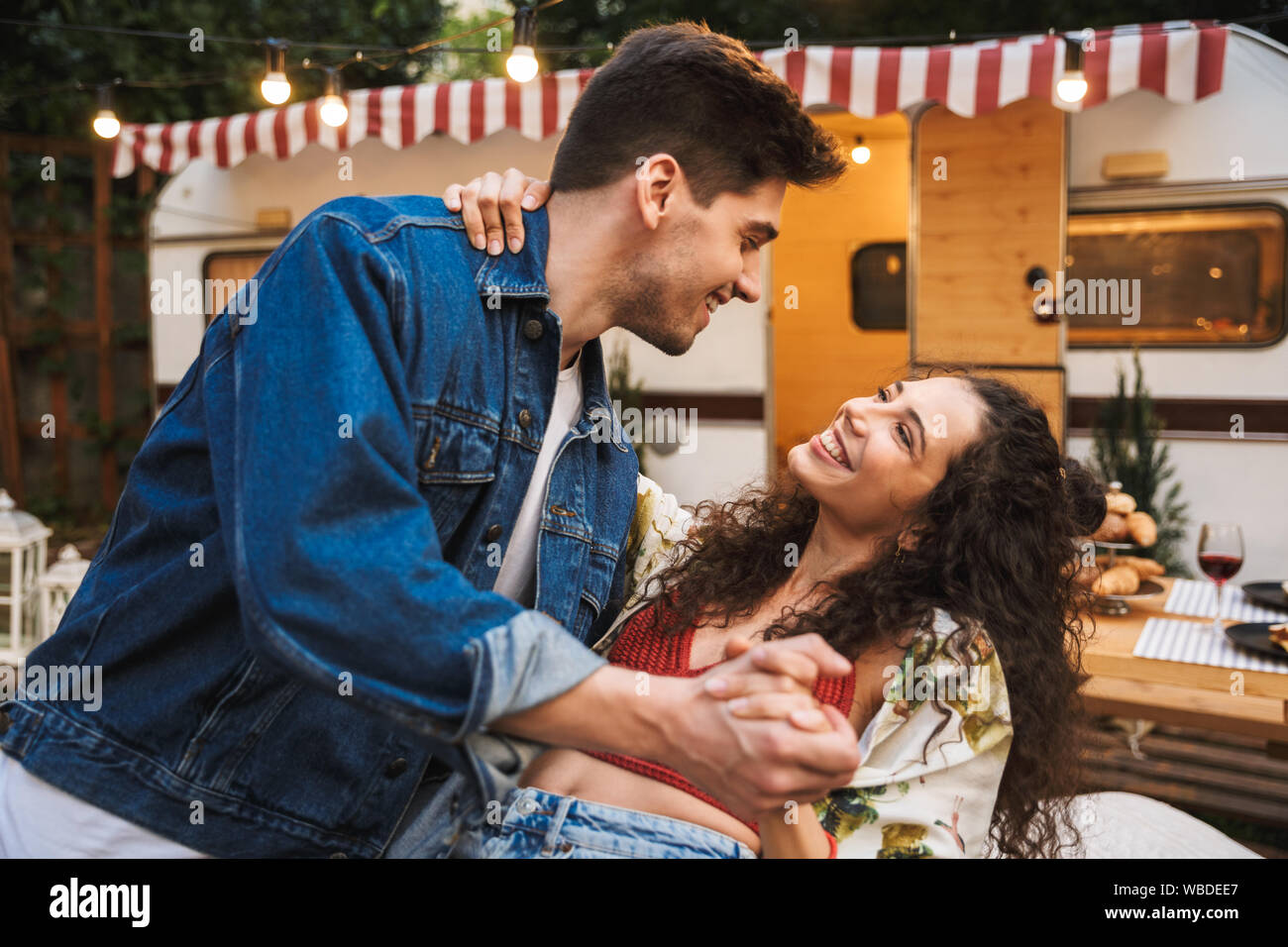 Ritratto di una seducente giovane uomo e donna sorridente mentre ballano insieme vicino casa su ruote all'esterno Foto Stock