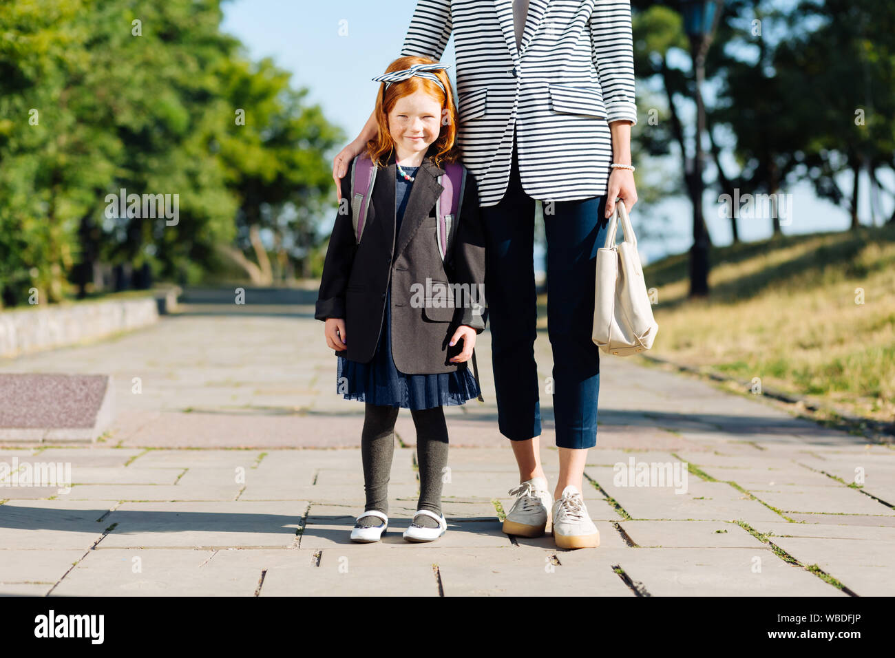 Affascinante piccolo ragazza in piedi vicino alla sua mamma Foto Stock