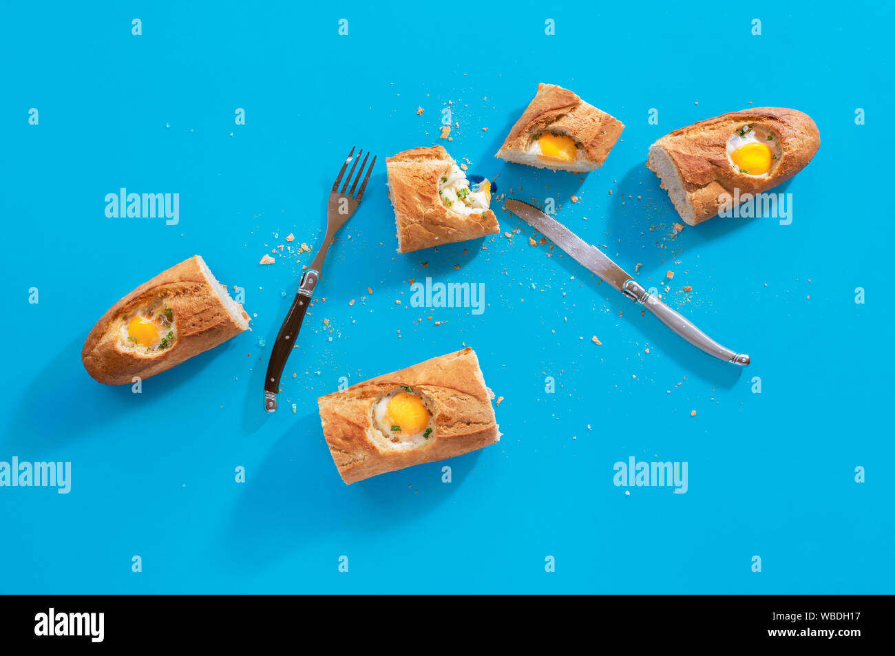 La colazione pasto porzioni con uova in francese di pezzi di pane e posate su uno sfondo blu. Piatto di laici mattina cibo in presenza di luce solare. Stile minimal. Foto Stock