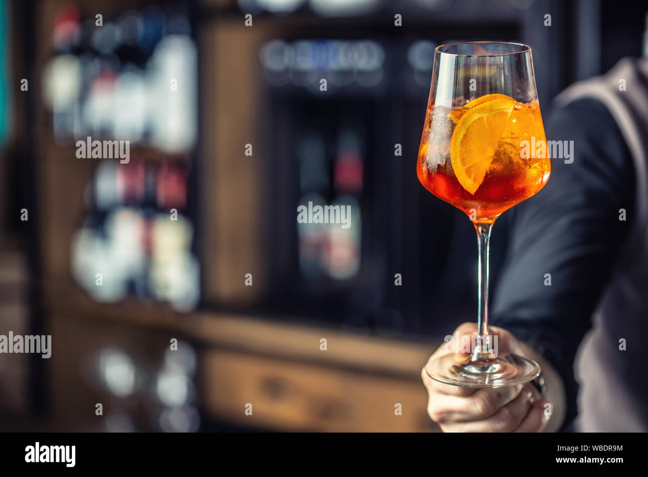 Aperol spritz drink. Barista mano che trattiene il vetro con Aperol Spritz drink Foto Stock