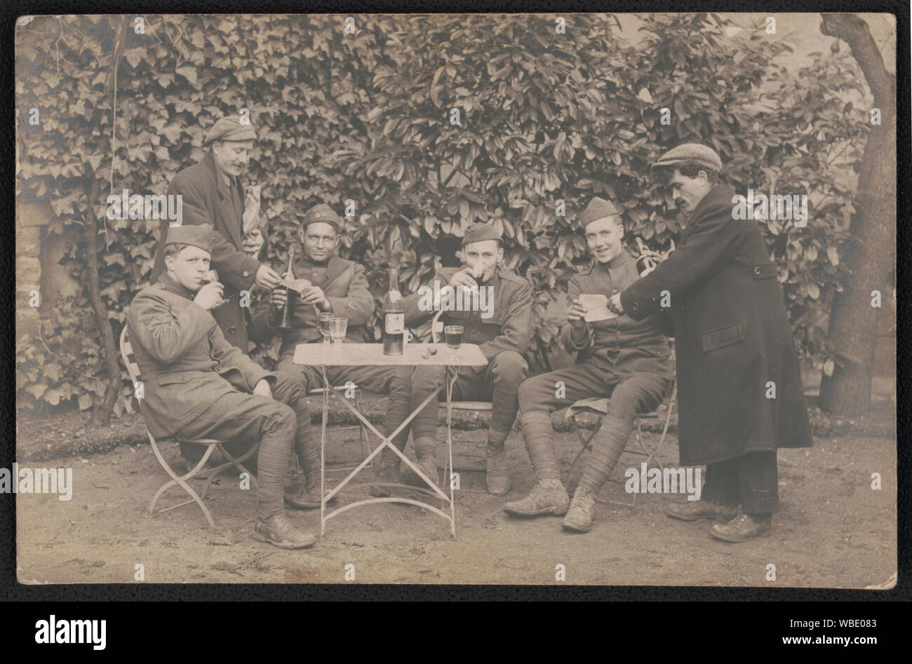 Quattro soldati non identificato in uniforme di bere il vino come due civili mano loro i documenti, probabilmente in Francia Riassunto/medio: 1 foto : gelatina silver stampa ; foglio 9 x 14 cm (formato cartolina) Foto Stock