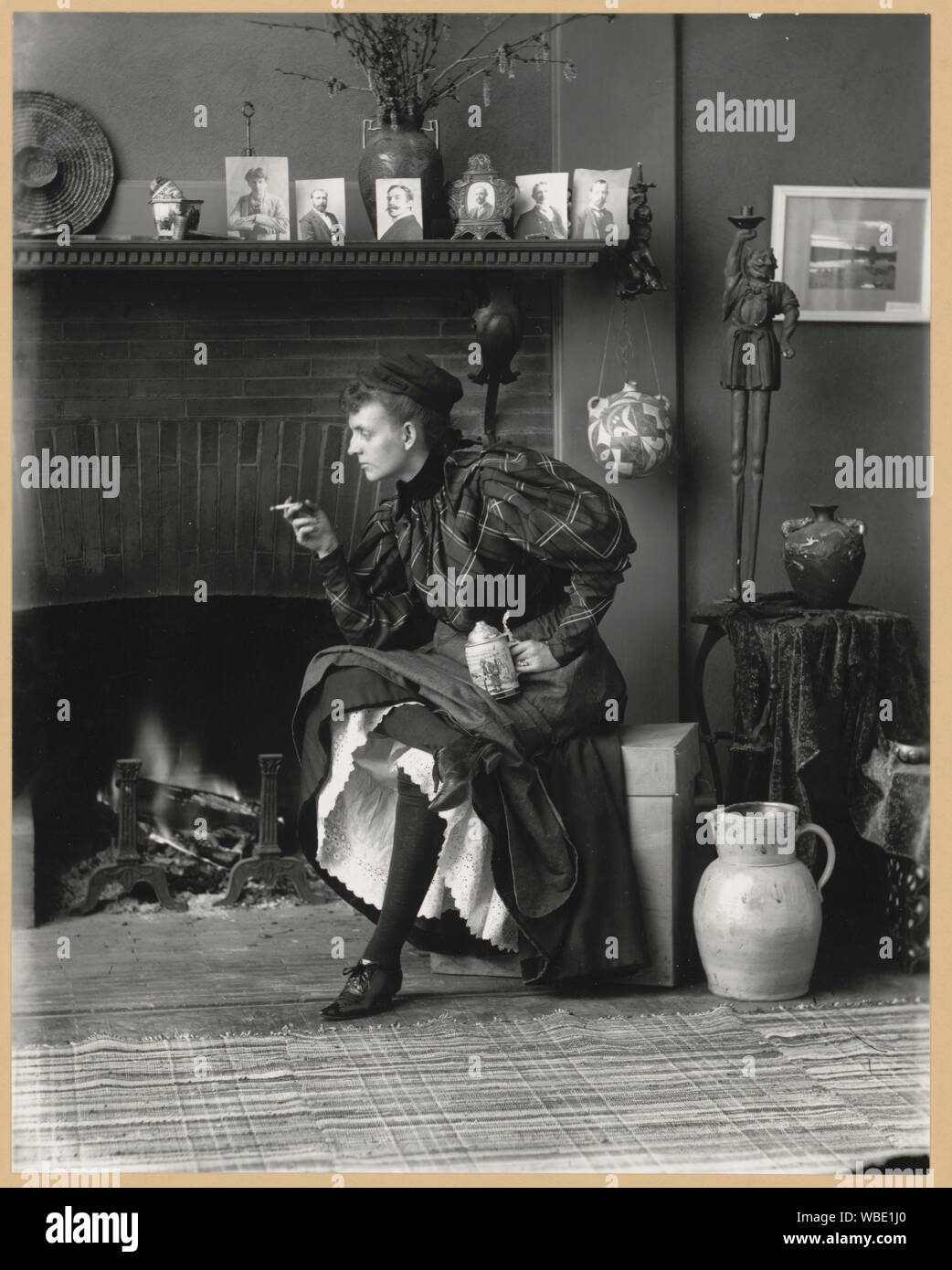 Frances Benjamin Johnston's autoritratto (come nuova donna), un full-length Self-portrait del suo seduti davanti al caminetto, rivolto verso sinistra, azienda di sigarette in una mano e una birra stein negli altri, nella sua Washington D.C. studio Foto Stock