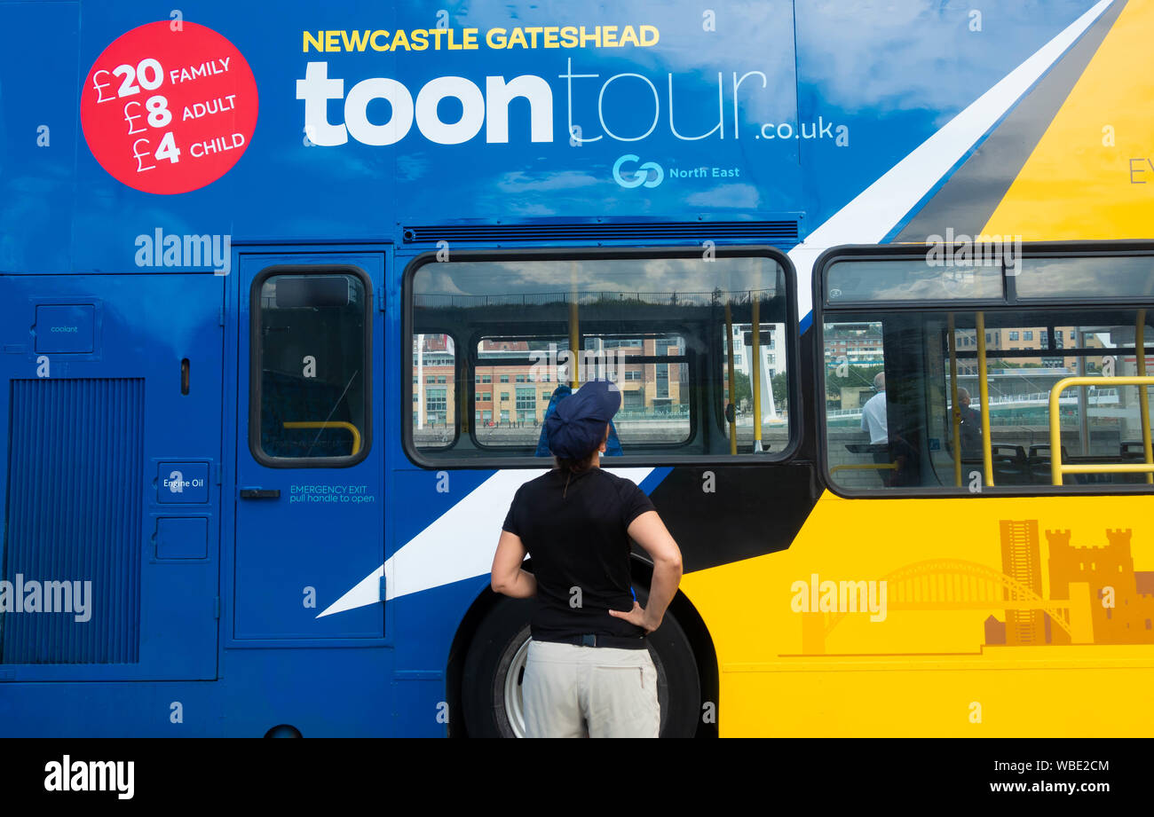 Turista femminile accanto a/Newcastle Gateshead open top tour bus. Newcastle upon Tyne, Inghilterra. Regno Unito Foto Stock