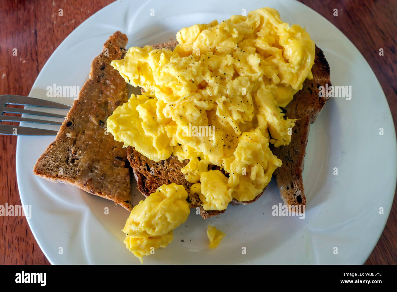 La colazione brunch o inizio pranzo in una caffetteria uova strapazzate su multi grano pane tostato Foto Stock