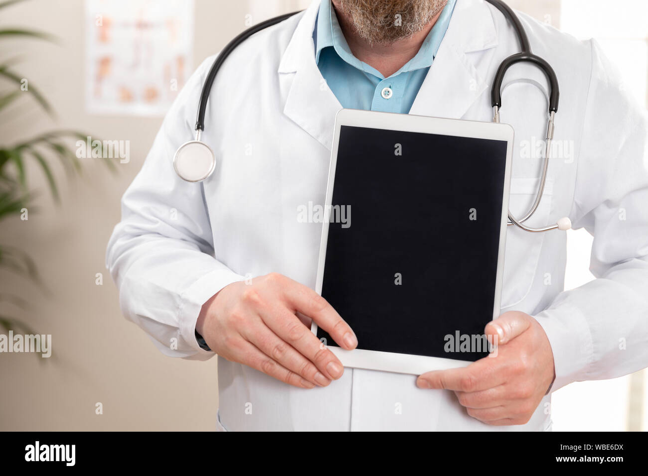 Maschio adulto medico che mostra un'immagine digitale o una relazione su una tavoletta grafica Foto Stock