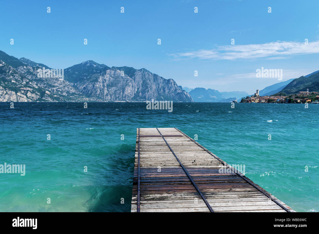 Dock in legno aggettante internamente al turquosie acqua del lago di Garda. il villaggio di Malcesine Foto Stock