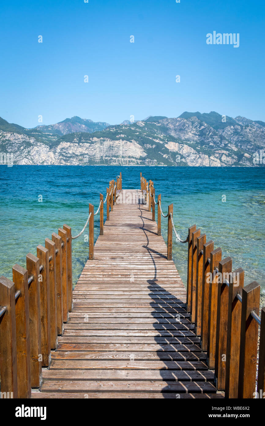 Dock in legno aggettante internamente al turquosie acqua del lago di Garda Foto Stock