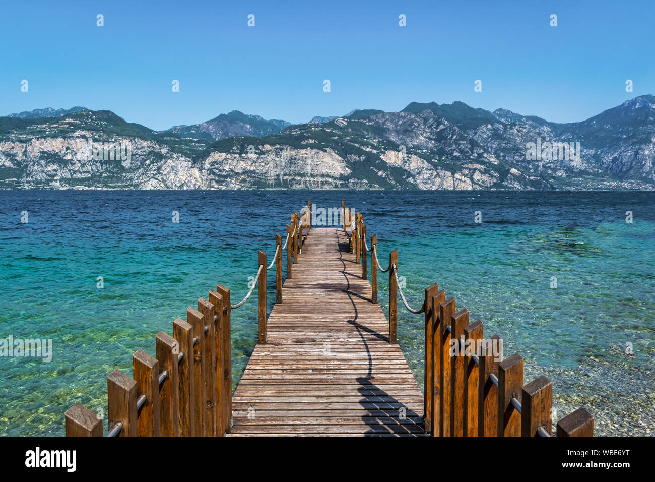 Dock in legno aggettante internamente al turquosie acqua del lago di Garda Foto Stock