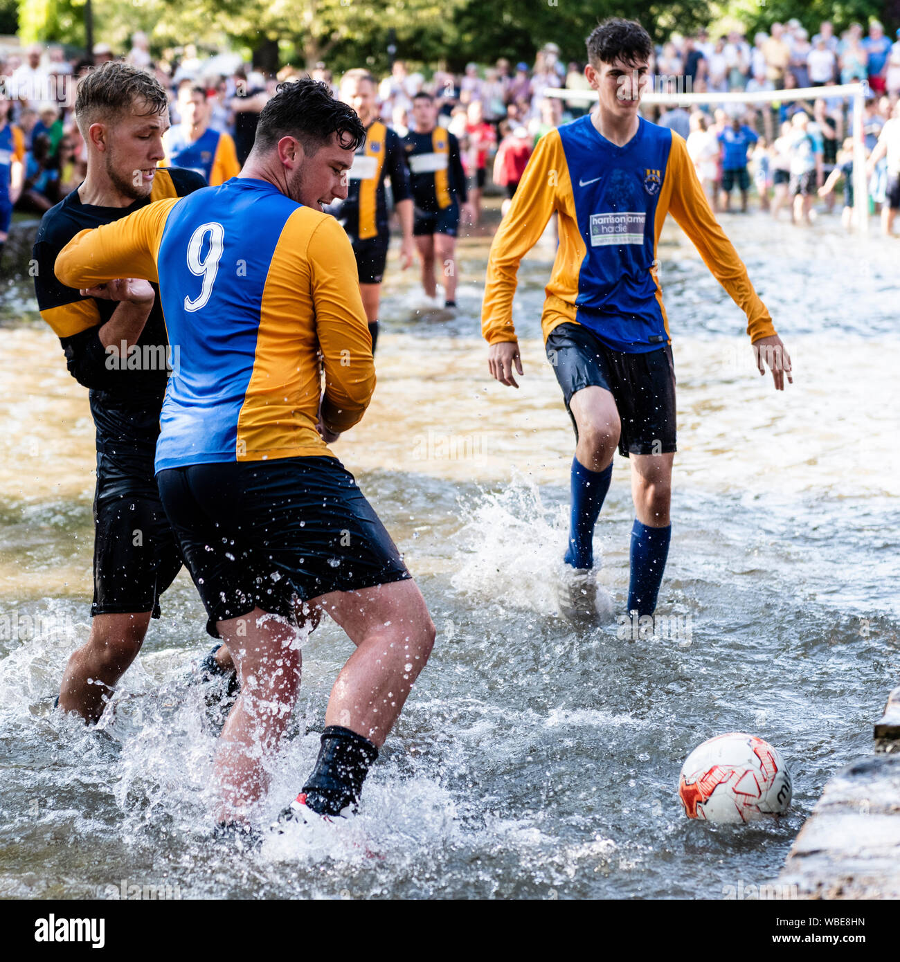 Partita di calcio di beneficenza giocato nel Fiume Windrush a Bourton-on-the-acqua, Cotswolds, UK. Gioco del calcio nel fiume su agosto lunedì festivo. Foto Stock