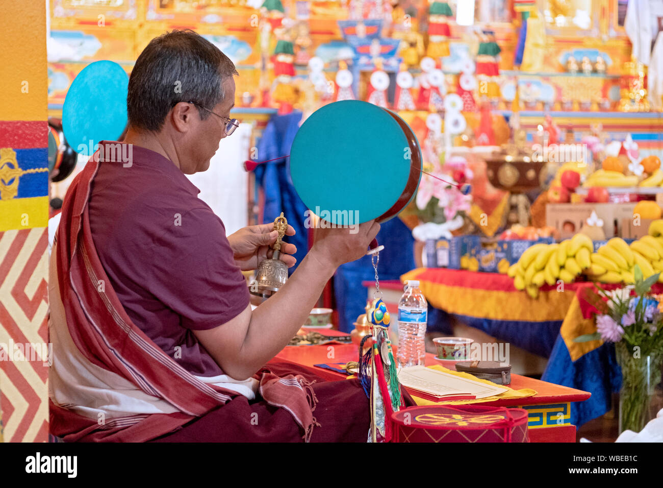 Un monaco buddista conduce una puja servizio in un tempio mentre il terminale voce squilla una campana e la rotazione di un tamburo damaru. In Elmhurst, Queens, a New York City. Foto Stock