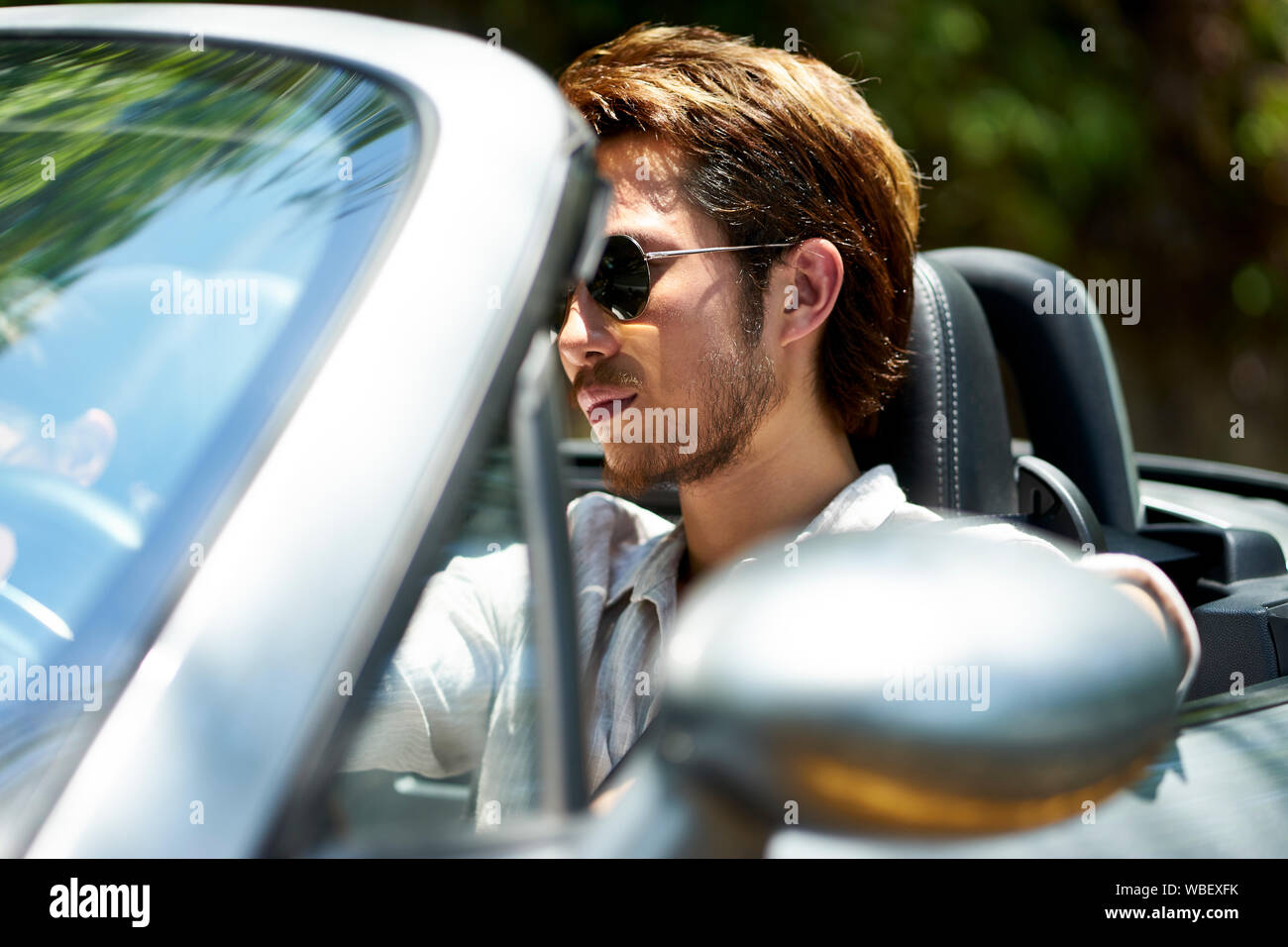 Giovane uomo asiatico alla guida di una vettura convertibile, close-up shot Foto Stock