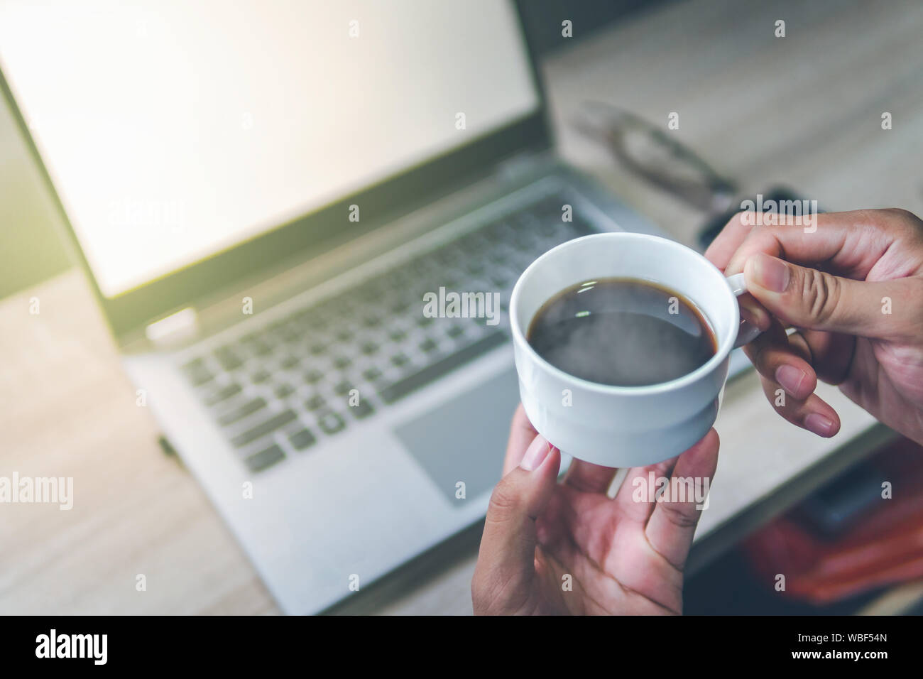 Imprenditori che stanno sorseggiando un caffè la mattina, concentrandosi sulle tazze da caffè vi è un computer notebook sfondo vista superiore. Foto Stock