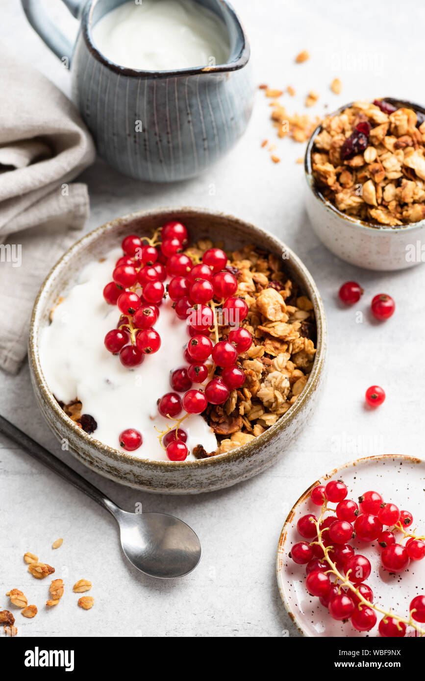 Crunchy granola con lo yogurt naturale e rosse bacche Ribes. Pulire mangiare, dieta e fitness concetto di menu. Il cibo della colazione ancora vita Foto Stock