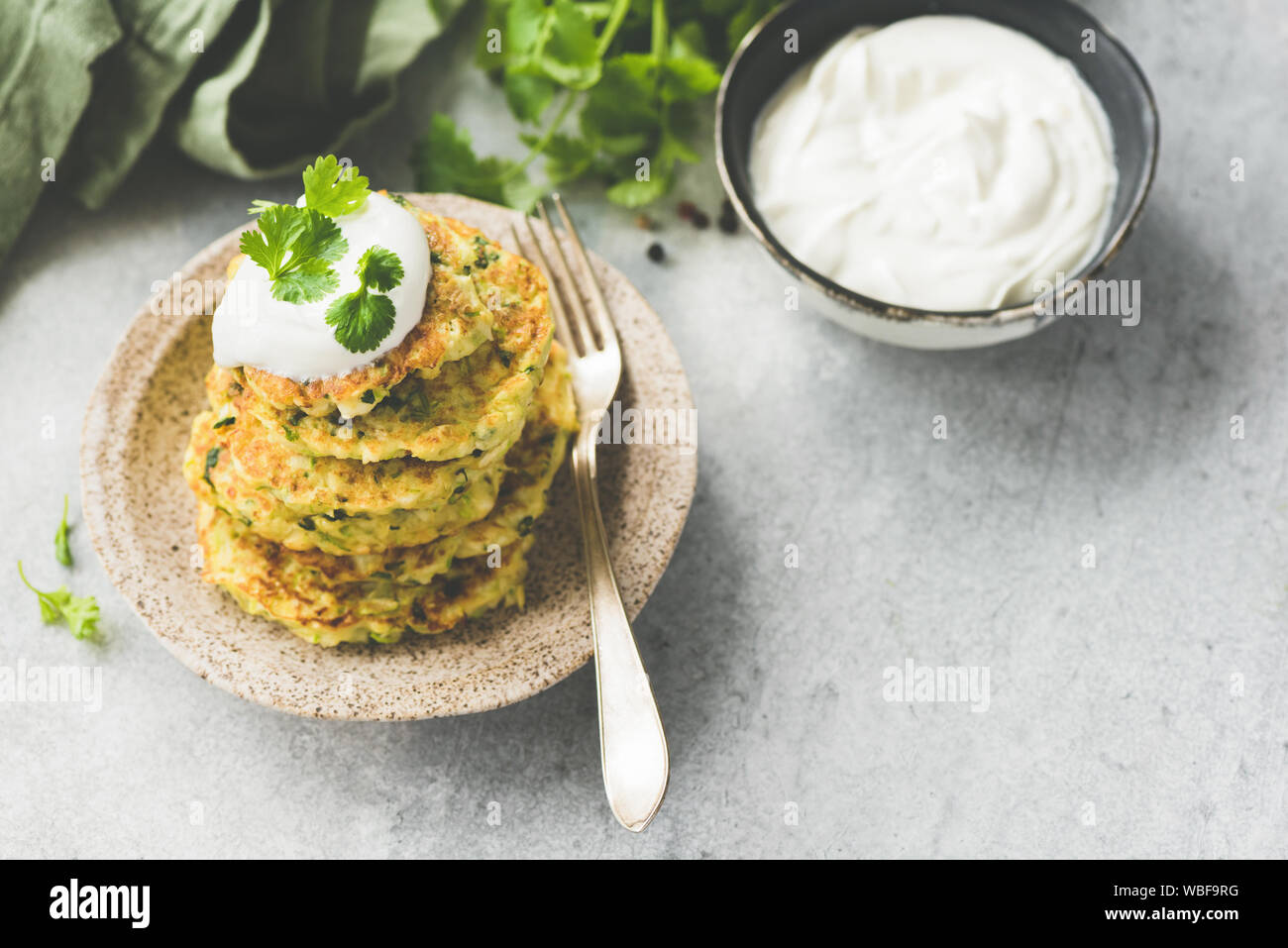 Frittelle di vegetali di zucchine, cavolo, Patate servita con panna acida e di coriandolo fresco. Copia dello spazio. Immagine dai toni Foto Stock