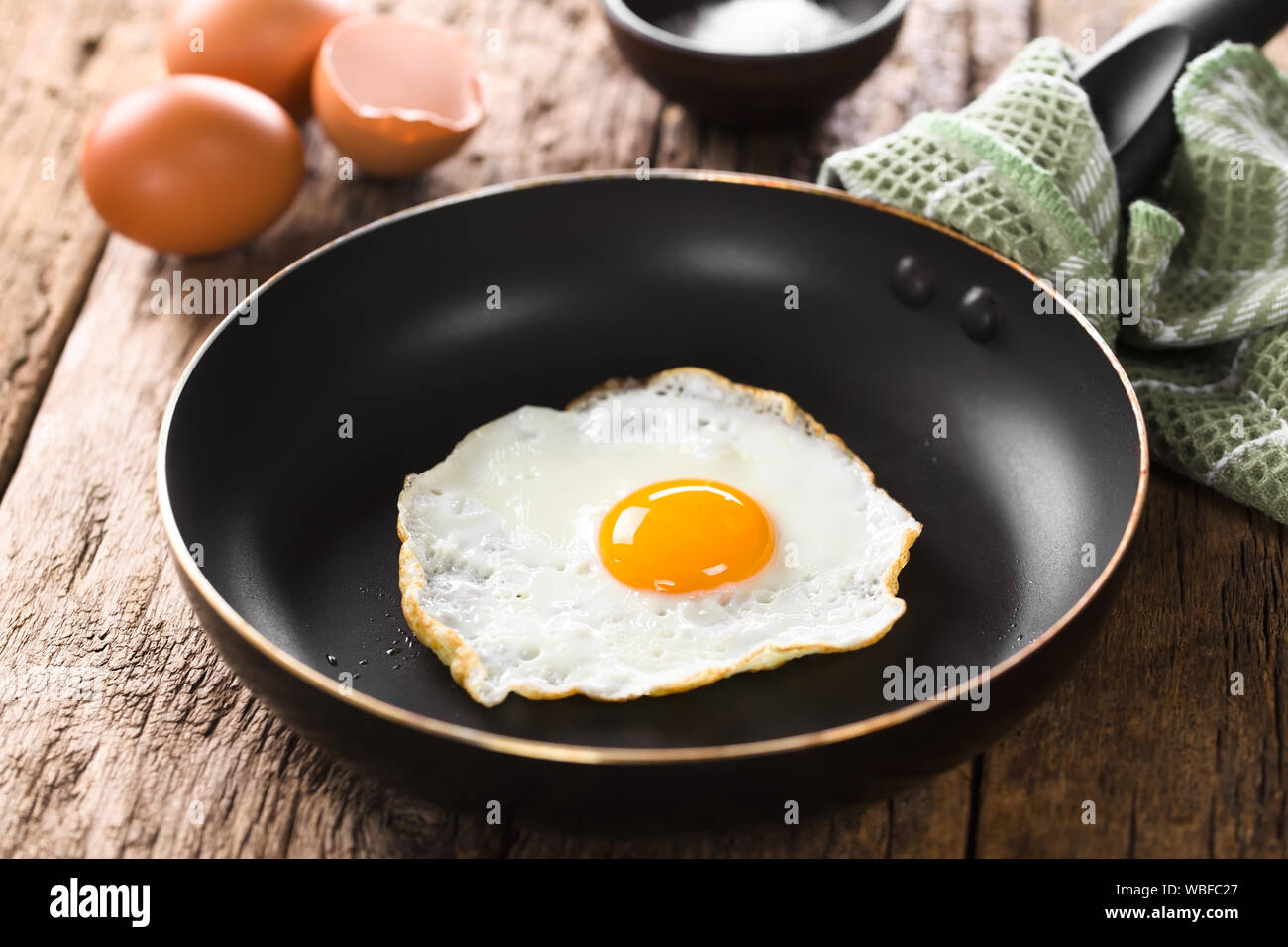 Una fresca uovo fritto sunny side fino in padella (messa a fuoco selettiva, messa a fuoco sulla parte anteriore del tuorlo d'uovo) Foto Stock