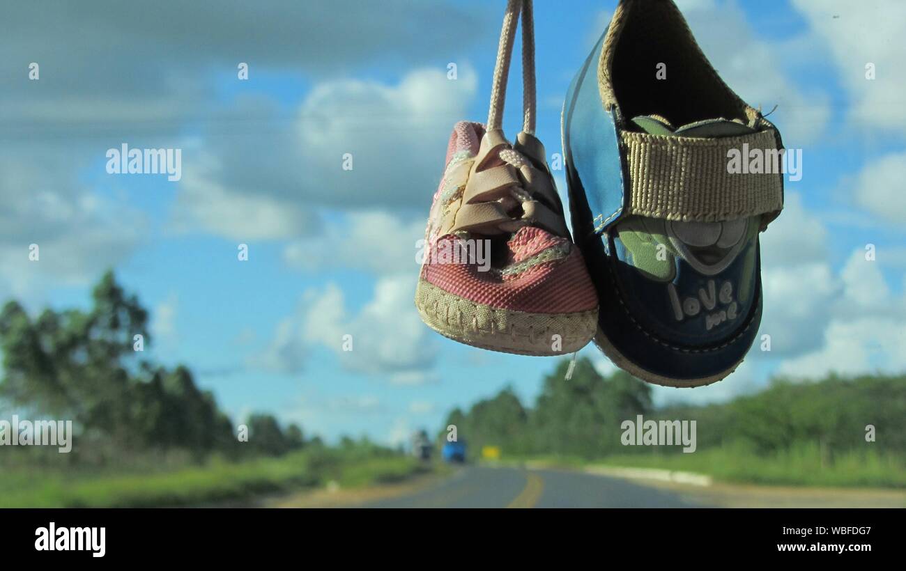 Close-up di scarpe per bambini appeso sul parabrezza per auto contro Sky  Foto stock - Alamy