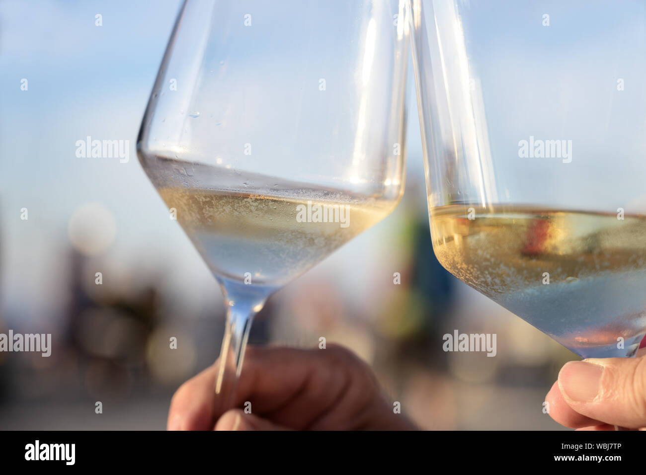 Toast con il freddo il vino bianco sulla soleggiata una sera d'estate durante le vacanze, il concetto di divertimento e stile di vita, close-up Foto Stock