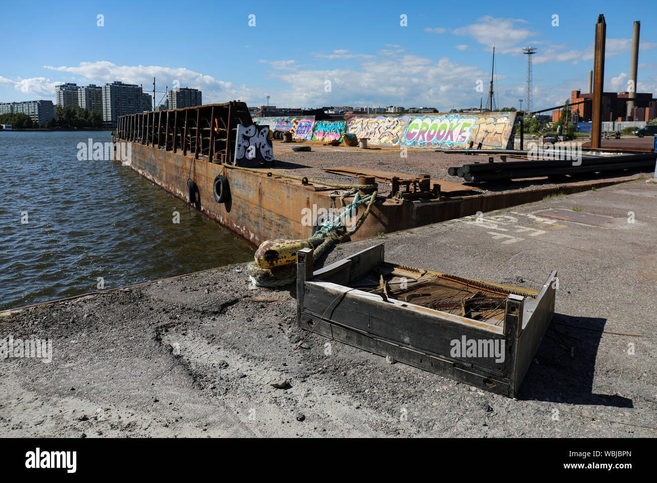 Rotture di pianoforte e un arrugginito barge in Sompasaari wasteland, Merihaka distretto in background, a Helsinki in Finlandia Foto Stock