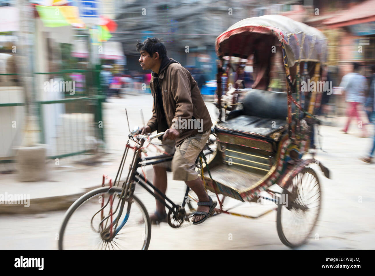 Il nepalese uomo che cavalca il suo ciclo in rickshaw Thahity Chowk, Kathmandu, Nepal Foto Stock