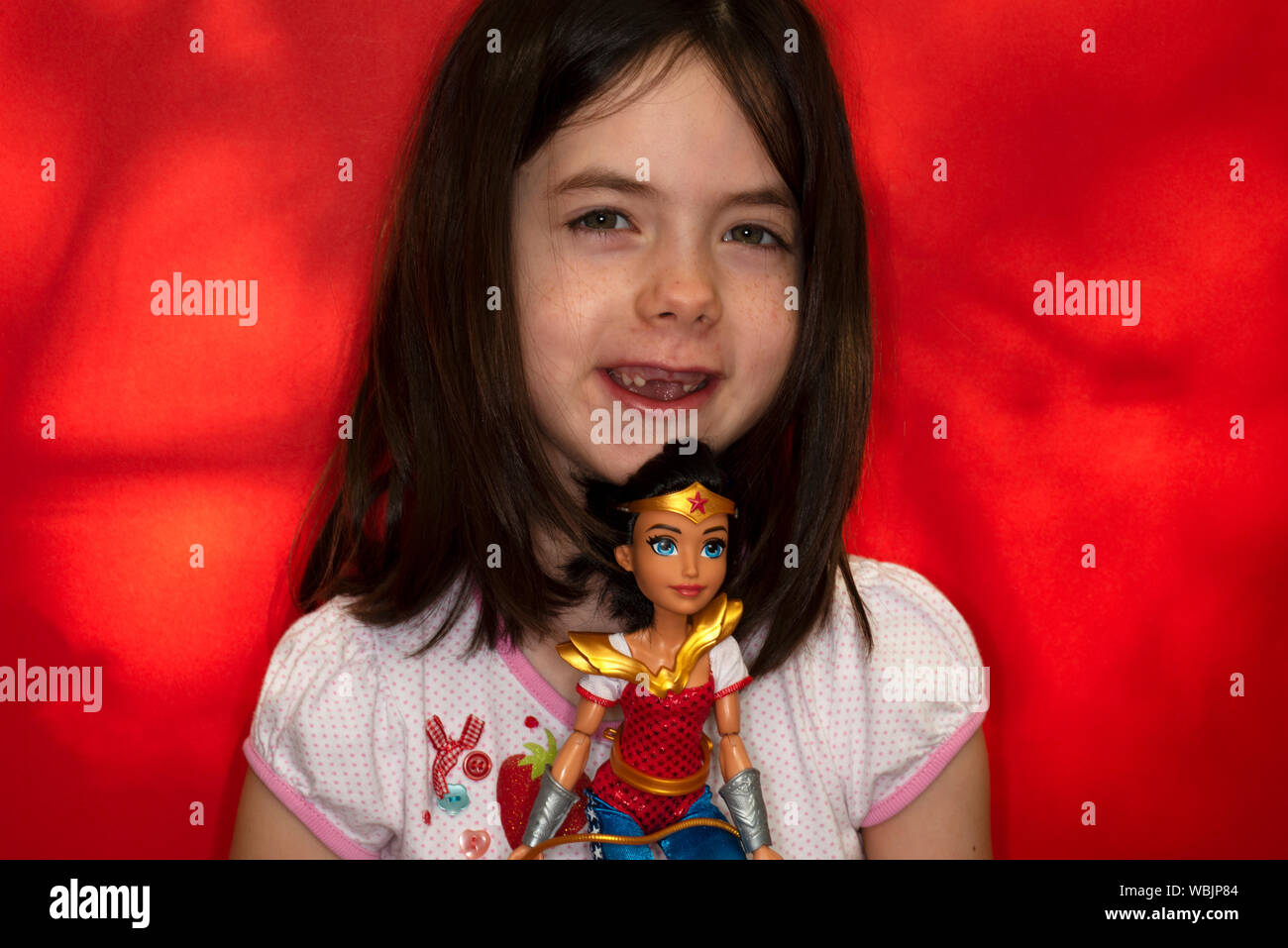 Ragazza giovane azienda Wonder Woman bambola giocattolo Foto Stock