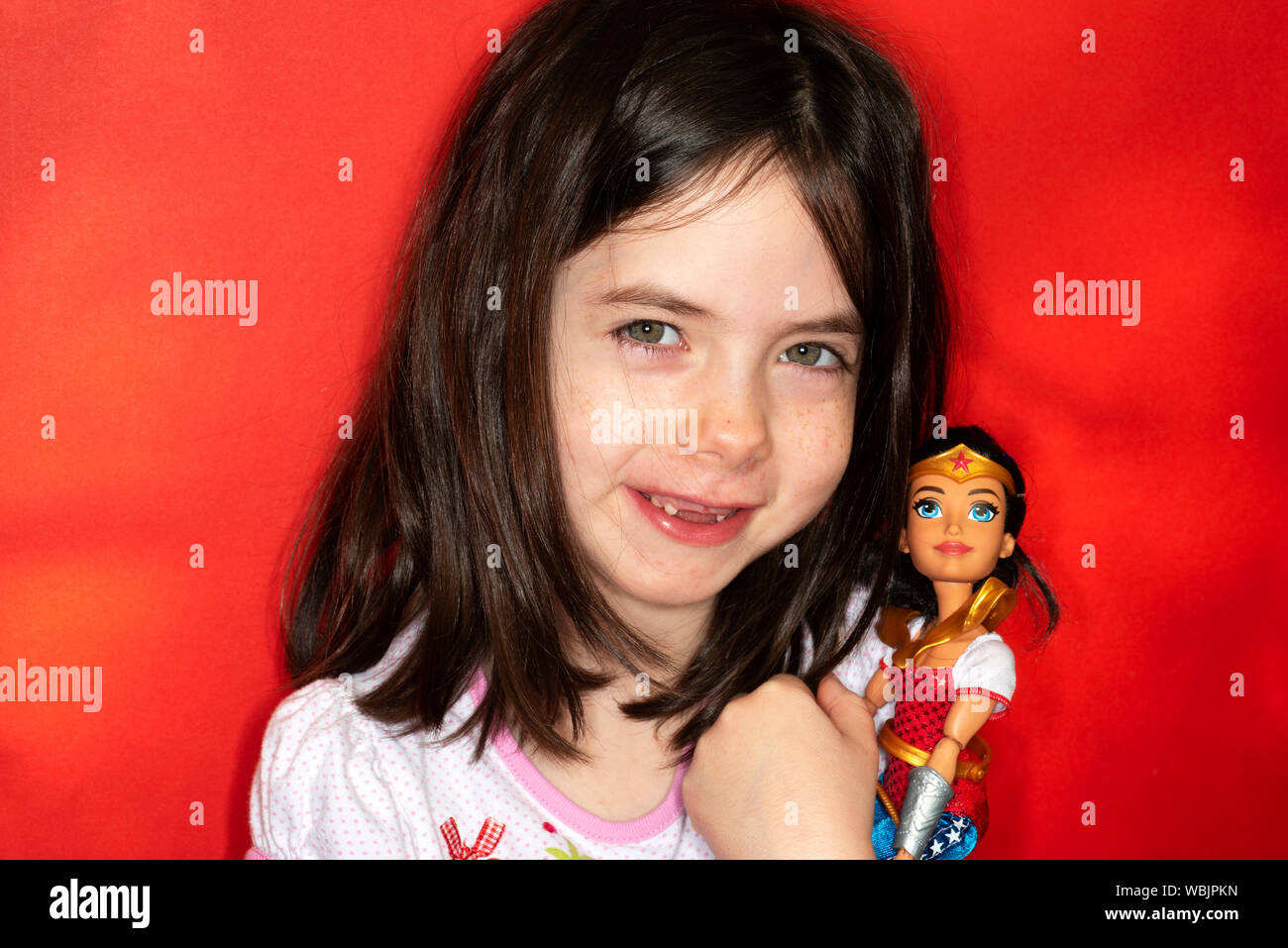 Ragazza giovane azienda Wonder Woman bambola giocattolo Foto Stock