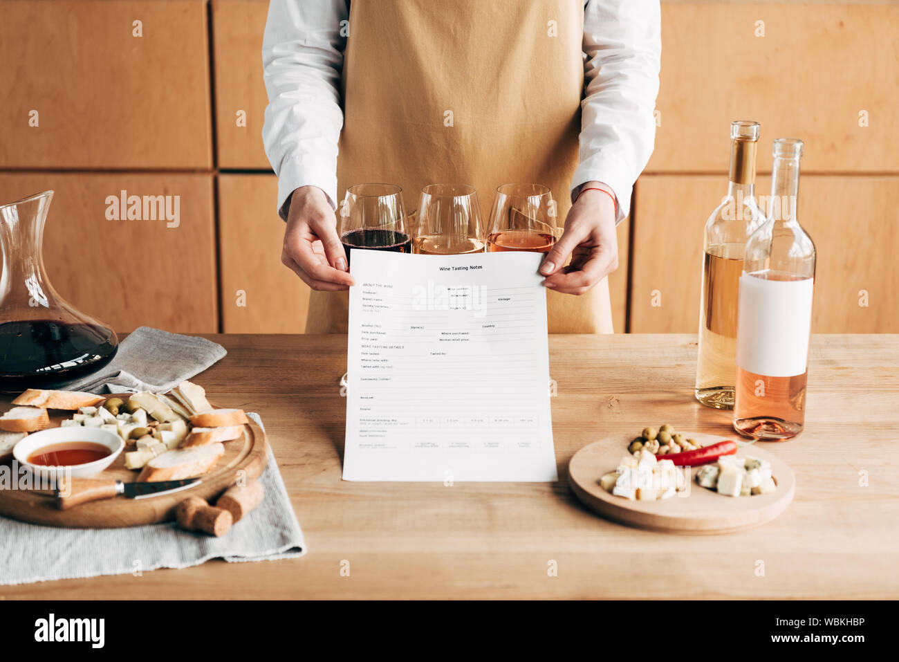 Vista ritagliata di sommelier in grembiule vino holding note di degustazione Foto Stock