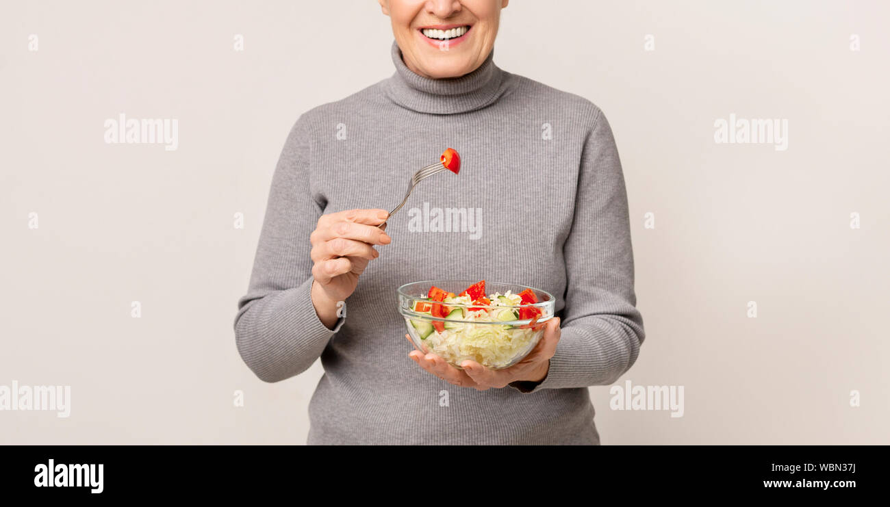 Mangiare sano. Felice di età della donna azienda ciotola di insalata di verdure Foto Stock