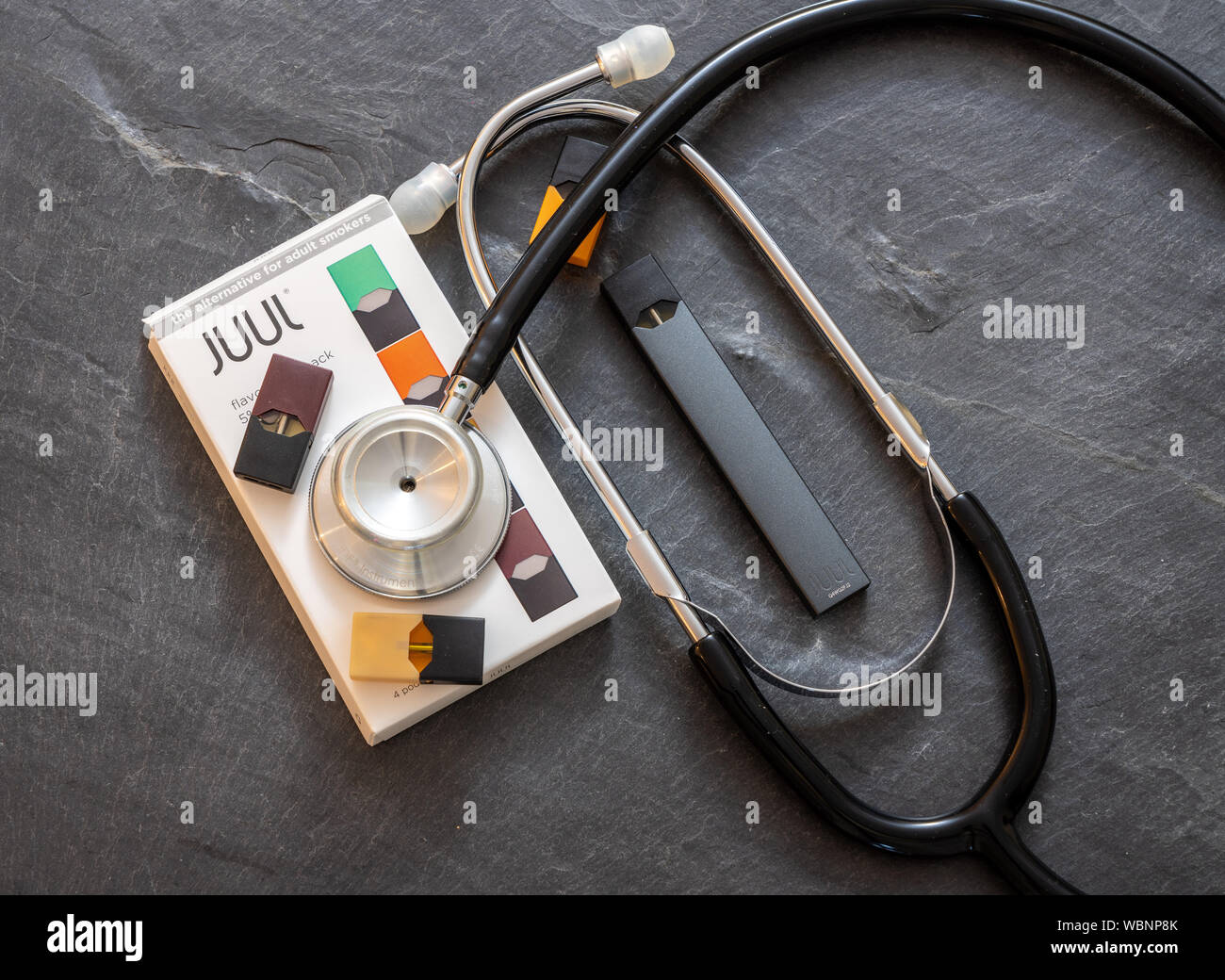 Casella azienda JUUL dispensatore di nicotina e baccelli con uno stetoscopio Foto Stock