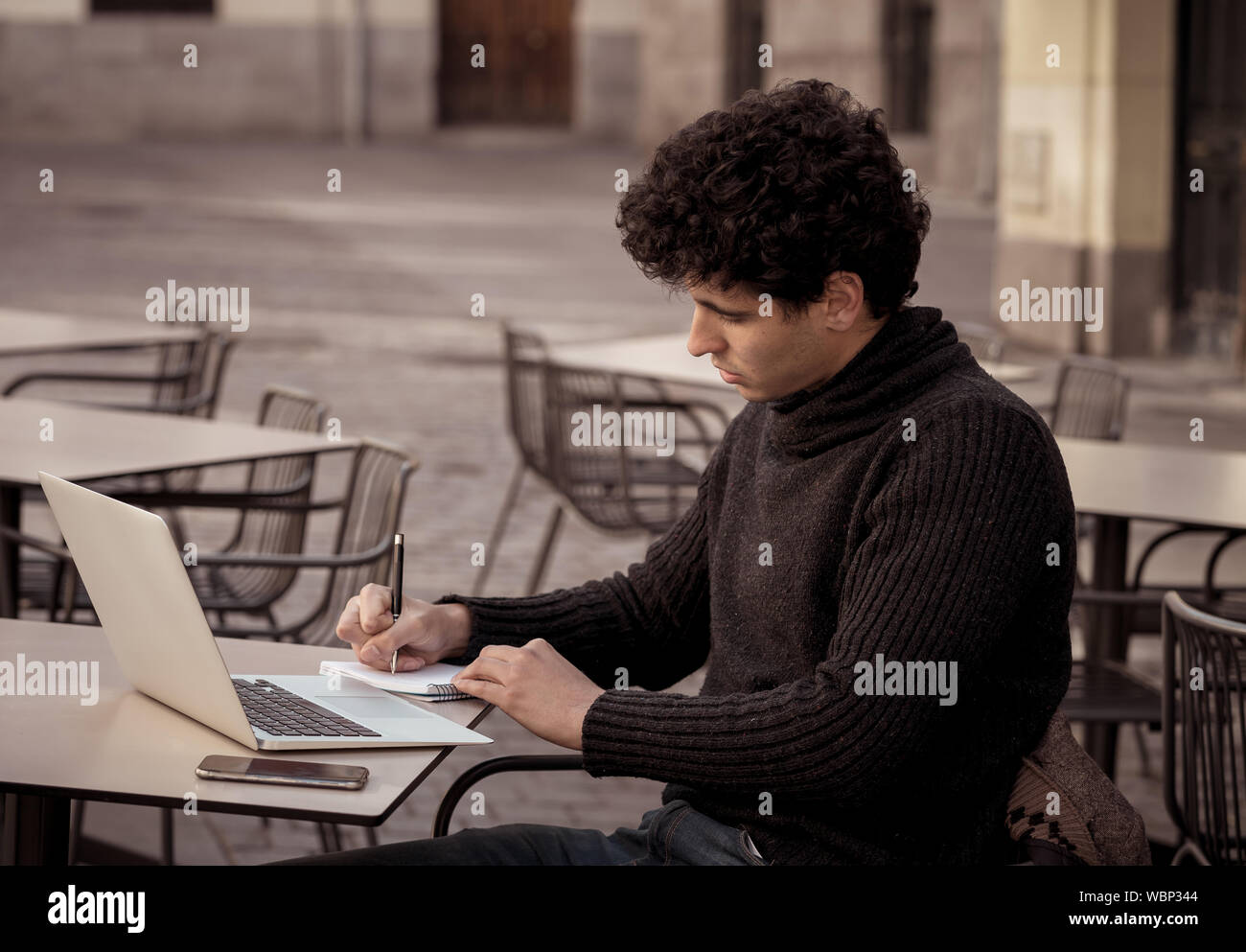 Bel giovane uomo che lavora sul computer portatile terrazza esterna in una città europea coffee shop. Studente sentirsi felice e soddisfatto. In viaggio intorno e Foto Stock