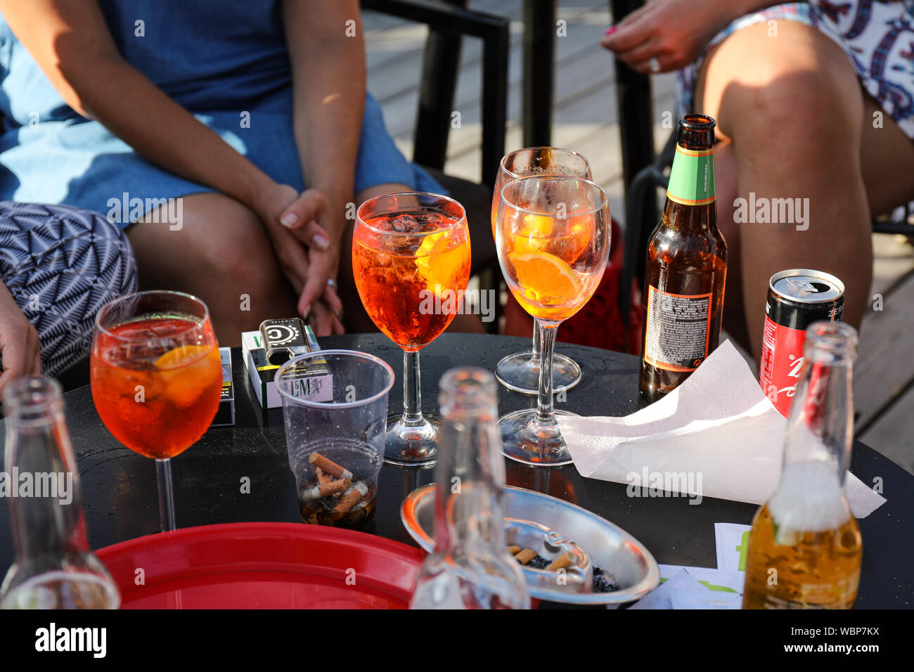 Bibite estive sul tavolo con un irriconoscibile femmine sullo sfondo Foto Stock