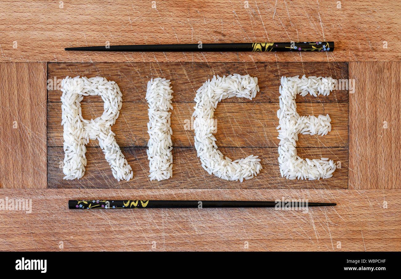 "Riso" parola scritta con chicchi di riso, incorniciato da bacchette nere. Foto Stock